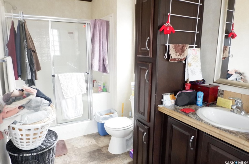 Ensuite Bathroom featuring a shower with shower door, tile floors, vanity, and toilet