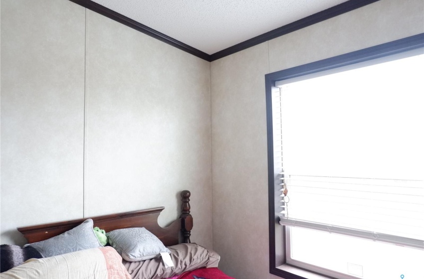 Bedroom featuring multiple windows, ornamental molding, and a textured ceiling