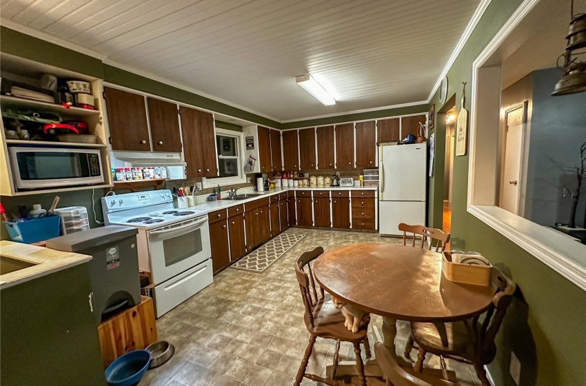 Kitchen featuring light flooring, sink, white appliances, and dark brown cabinetry