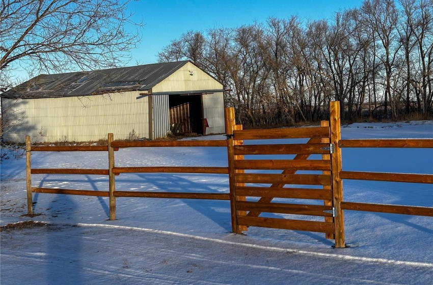 Snow covered gate featuring a pole shed