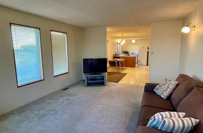 Living room featuring light carpet floors and a notable chandelier