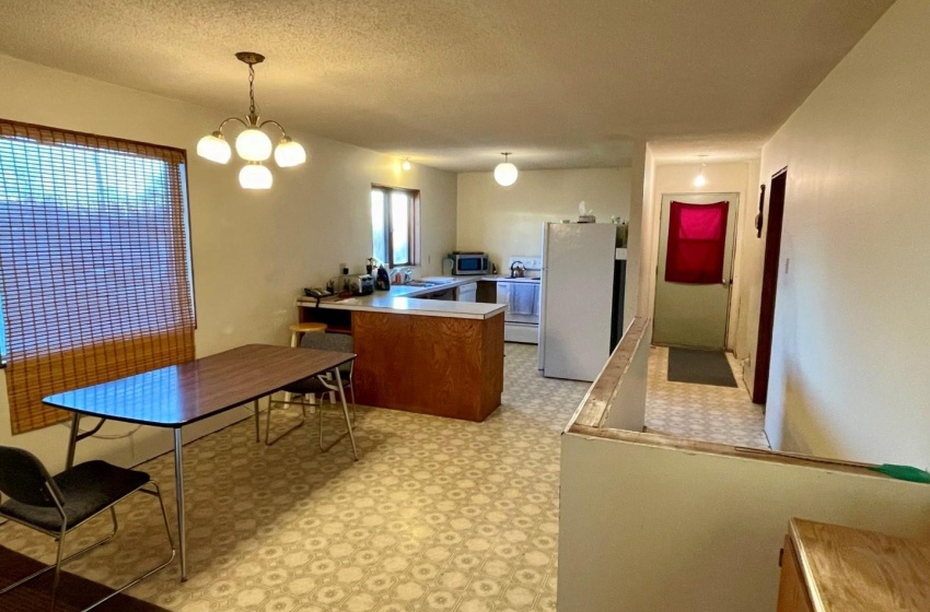 Kitchen featuring light linoleum floors, white refrigerator, a textured ceiling, hanging light fixtures, and an inviting chandelier