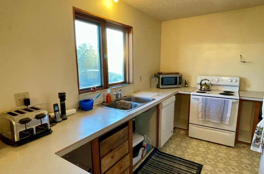 Kitchen featuring white appliances, a textured ceiling, sink, and light  linoleum floors