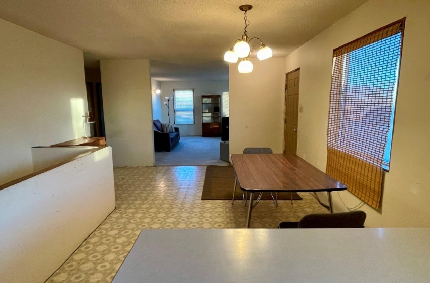 Dining area, linoleum floor, with an inviting chandelier and a textured ceiling.