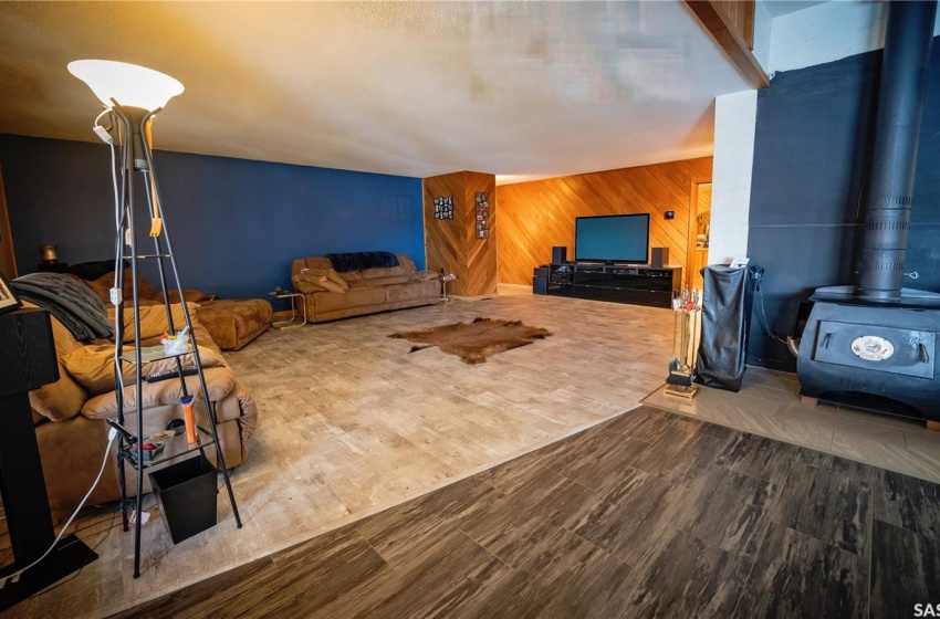 Living room featuring wood walls, a wood stove, and wood-type flooring