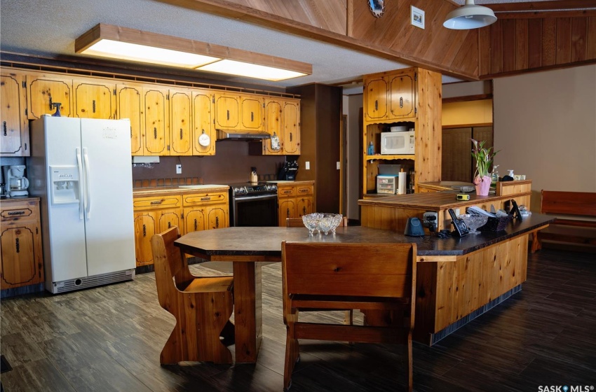 Kitchen featuring white appliances, dark wood-type flooring, and a textured ceiling