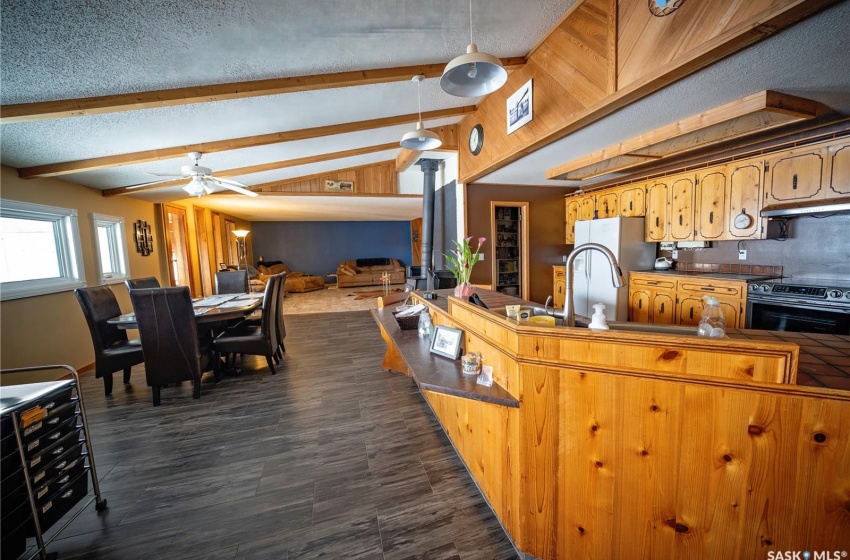 Kitchen with vaulted ceiling with beams, a textured ceiling, ceiling fan, decorative light fixtures, and black electric range