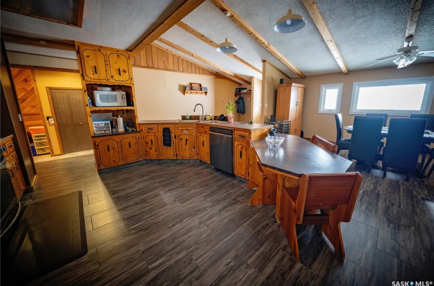 Kitchen with lofted ceiling with beams, dark hardwood / wood-style flooring, a textured ceiling, and stainless steel dishwasher