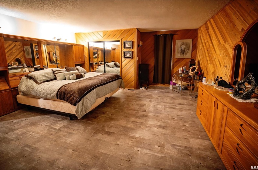 Bedroom featuring light wood-type flooring, wooden walls, and a textured ceiling