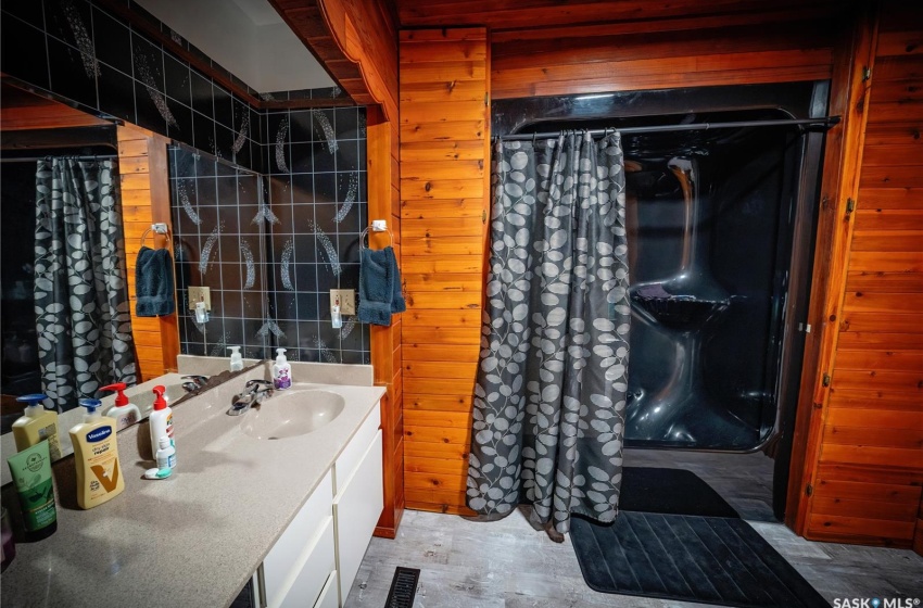 Bathroom featuring large vanity, wooden walls, and tile flooring