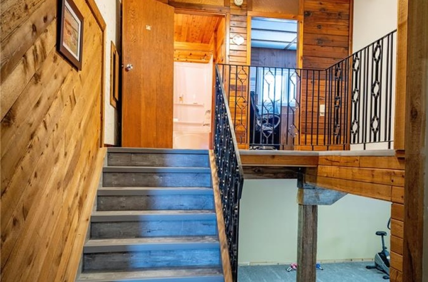 Stairs with dark hardwood / wood-style flooring, wooden walls, and ceiling fan