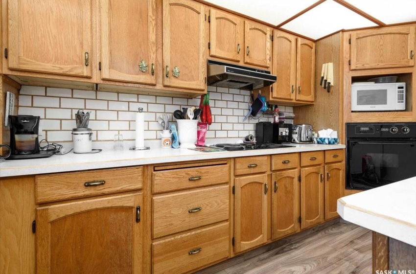 Kitchen featuring tasteful backsplash, white microwave, light hardwood / wood-style flooring, and oven