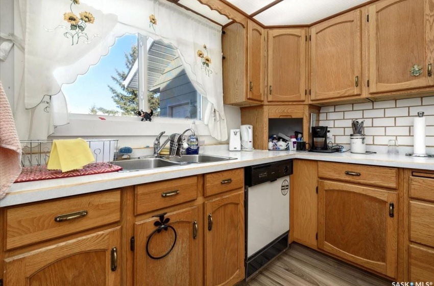 Kitchen with backsplash, white dishwasher, sink, and light hardwood / wood-style floors