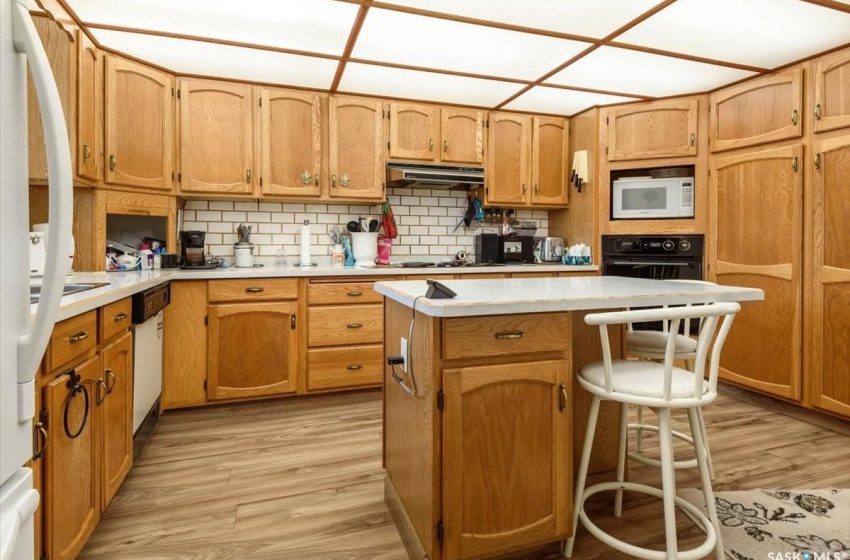 Kitchen featuring a kitchen breakfast bar, light wood-type flooring, black appliances, a kitchen island, and backsplash