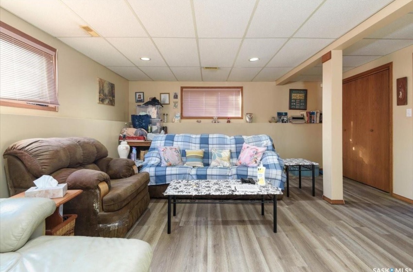 Living room with a drop ceiling and light hardwood / wood-style floors