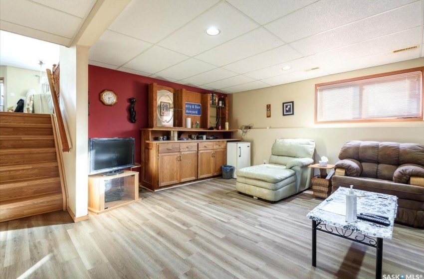 Living room with a drop ceiling and light hardwood / wood-style floors