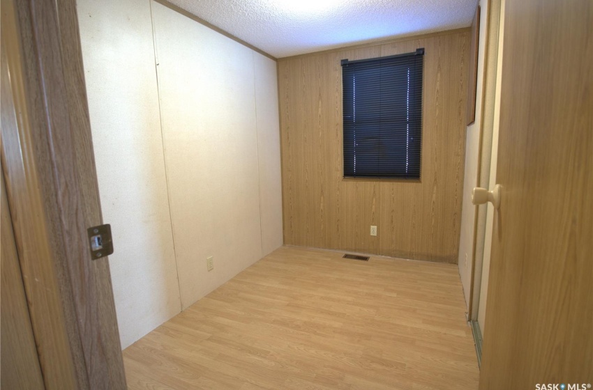 Empty room featuring light hardwood / wood-style flooring, wood walls, and a textured ceiling