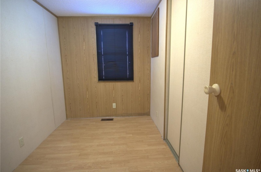 Hallway featuring light hardwood / wood-style flooring, wooden walls, and a textured ceiling