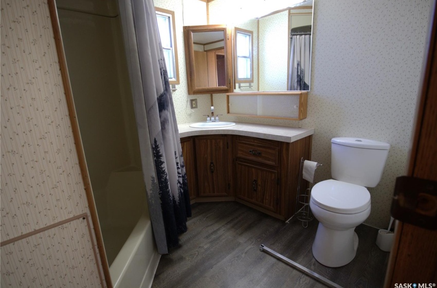 Full bathroom with shower / bathtub combination with curtain, toilet, hardwood / wood-style floors, and vanity with extensive cabinet space