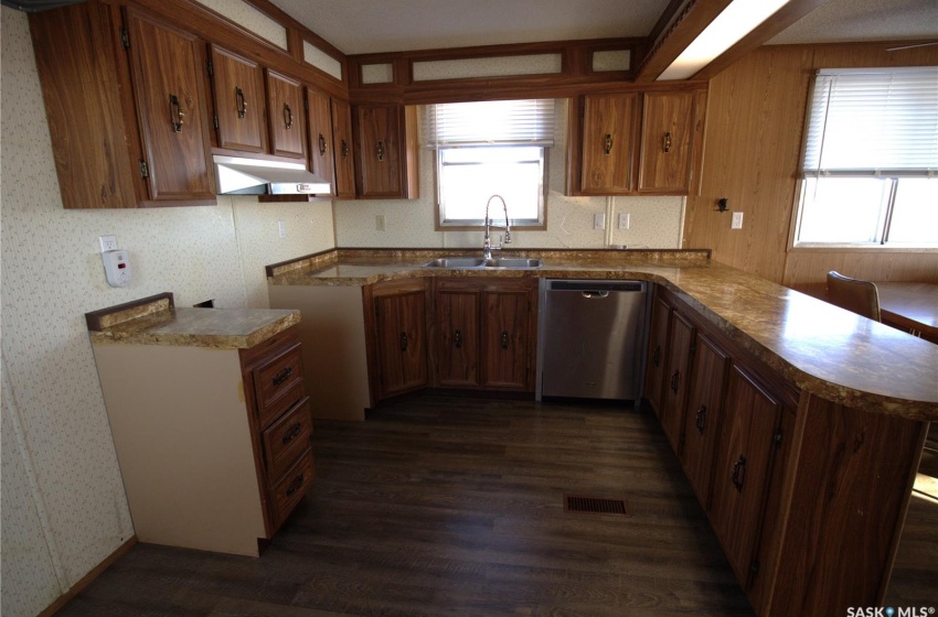 Kitchen with dark hardwood / wood-style flooring, kitchen peninsula, dishwasher, and sink