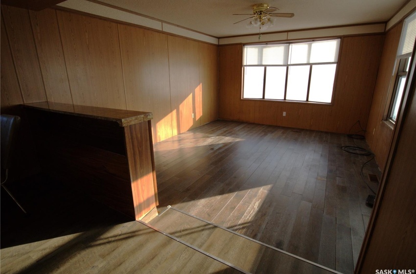 Unfurnished room featuring dark wood-type flooring, wooden walls, and ceiling fan