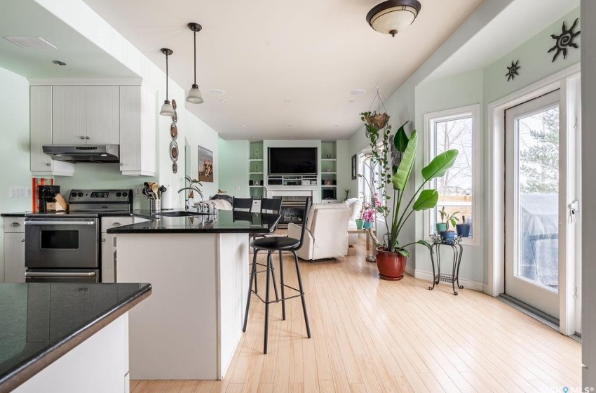 Kitchen with hanging light fixtures, light wood-type flooring, stainless steel range with electric cooktop, and white cabinetry