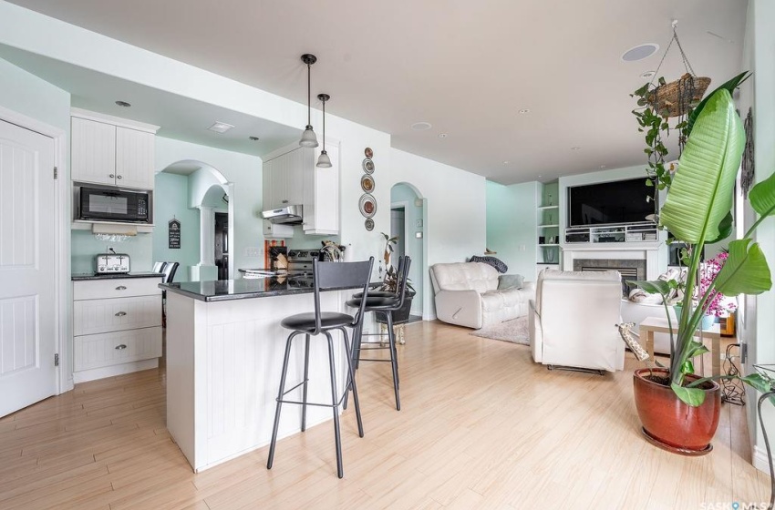 Kitchen featuring light hardwood / wood-style flooring, white cabinets, black microwave, a breakfast bar, and pendant lighting