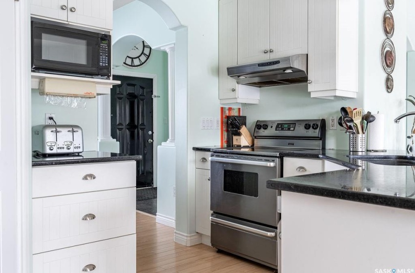 Kitchen featuring light hardwood / wood-style flooring, black microwave, white cabinetry, sink, and stainless steel electric range