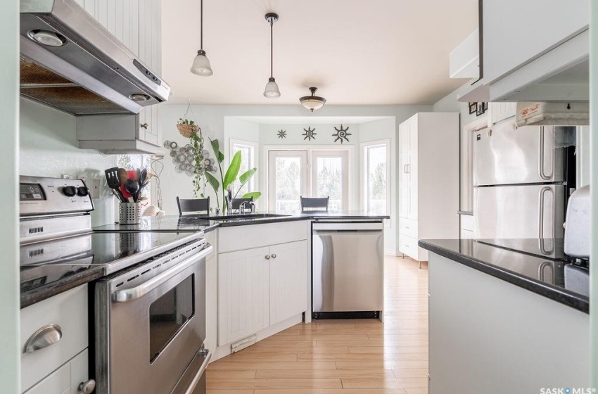 Kitchen featuring pendant lighting, stainless steel appliances, white cabinets, light hardwood / wood-style flooring, and sink