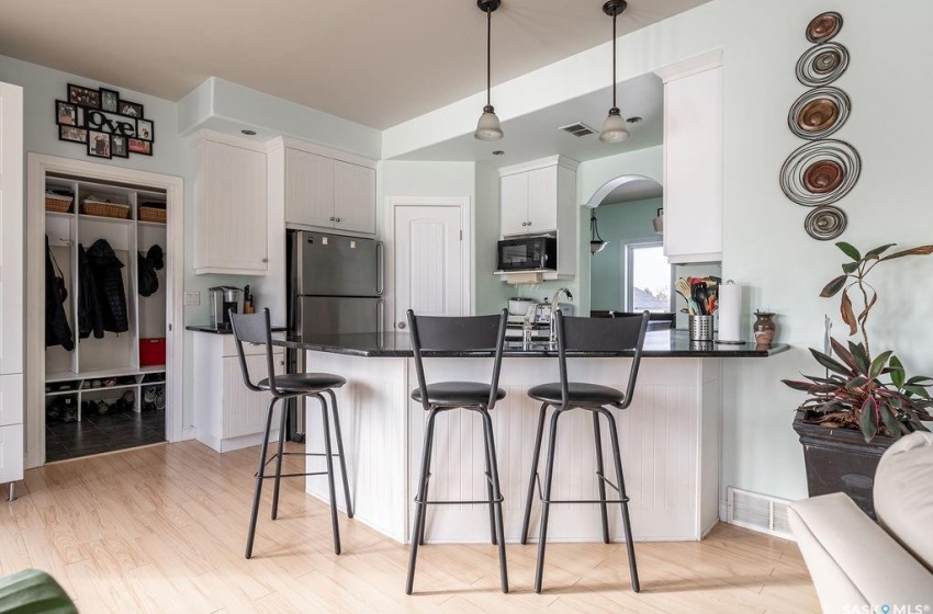 Kitchen with pendant lighting, stainless steel fridge, a breakfast bar, light hardwood / wood-style flooring, and black microwave