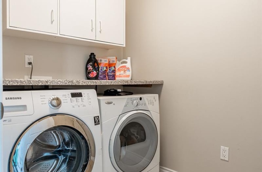 Laundry room with cabinets, light tile flooring, and washing machine and dryer