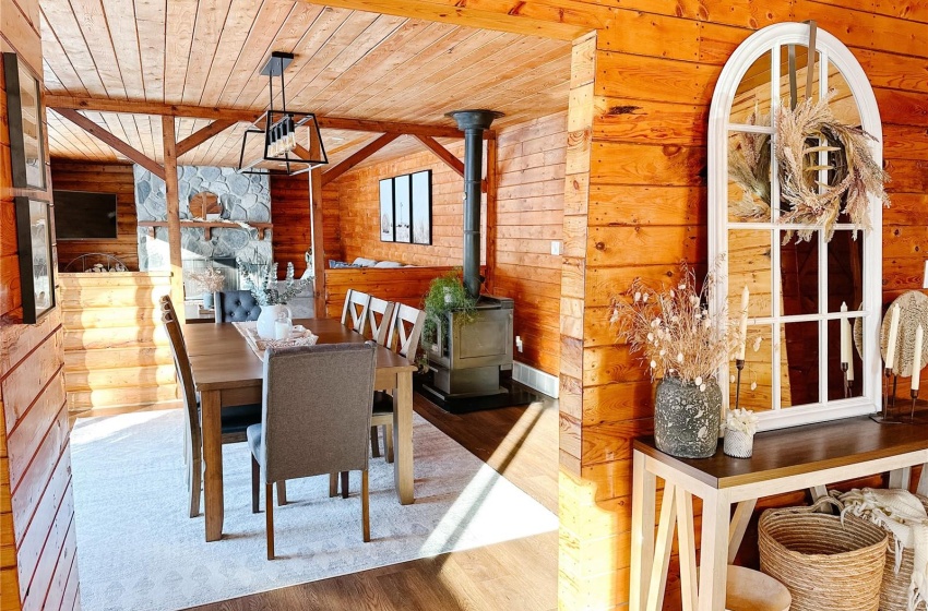 Dining area with hardwood / wood-style flooring, wood walls, wooden ceiling, and a wood stove