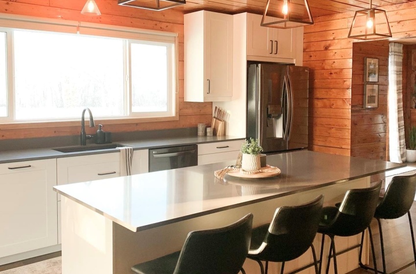 Kitchen with a kitchen island, appliances with stainless steel finishes, wooden walls, and a breakfast bar area