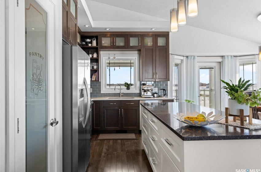 Kitchen featuring vaulted ceiling, dark brown cabinets, stainless steel refrigerator with ice dispenser, and white cabinetry