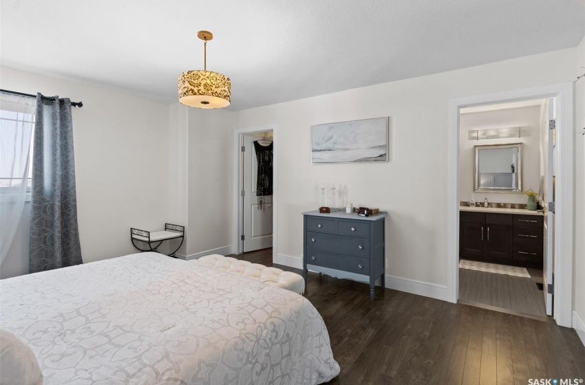 Bedroom featuring dark hardwood / wood-style flooring, sink, a walk in closet, and ensuite bath