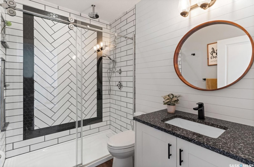 Bathroom with large vanity, wood walls, an enclosed shower, and toilet