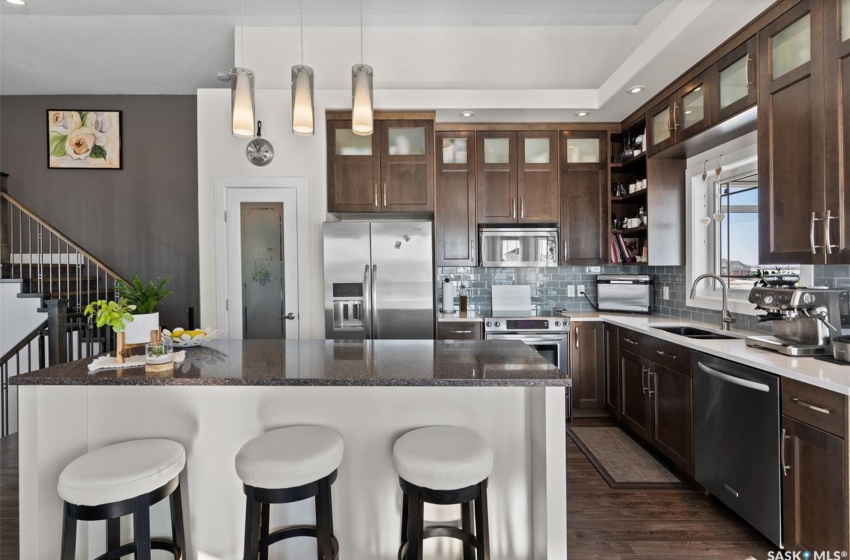 Kitchen with pendant lighting, dark hardwood / wood-style flooring, appliances with stainless steel finishes, a kitchen breakfast bar, and sink