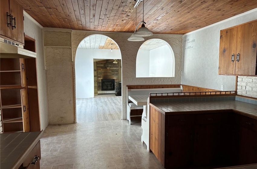 Kitchen with tile countertops, decorative light fixtures, wooden ceiling, and dark tile floors