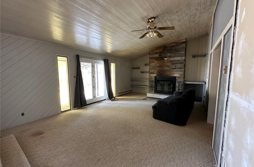 Unfurnished living room with a fireplace, light colored carpet, wood ceiling, wood walls, and ceiling fan