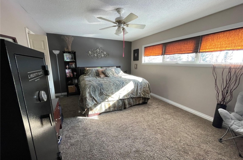 Bedroom featuring ceiling fan, dark carpet, and a textured ceiling