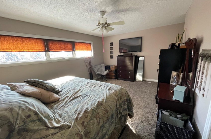 Bedroom with dark colored carpet, ceiling fan, and a textured ceiling