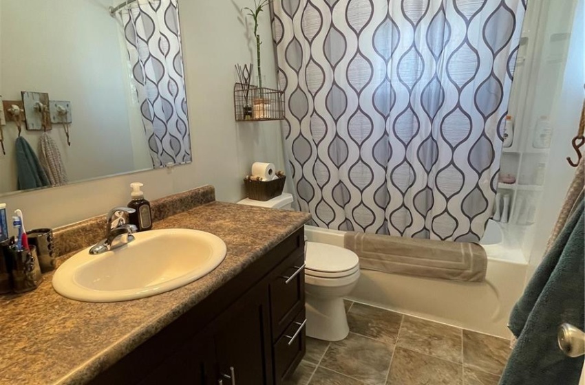 Full bathroom featuring shower / tub combo with curtain, vanity, tile flooring, and toilet