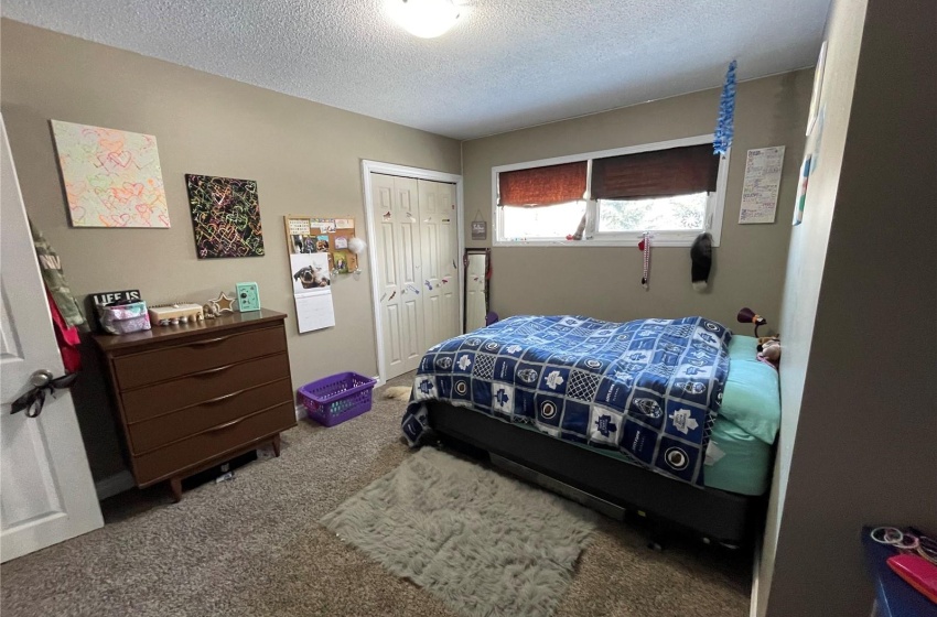 Bedroom featuring dark colored carpet, a closet, and a textured ceiling