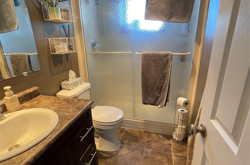 Bathroom featuring a shower with door, tile flooring, toilet, and vanity