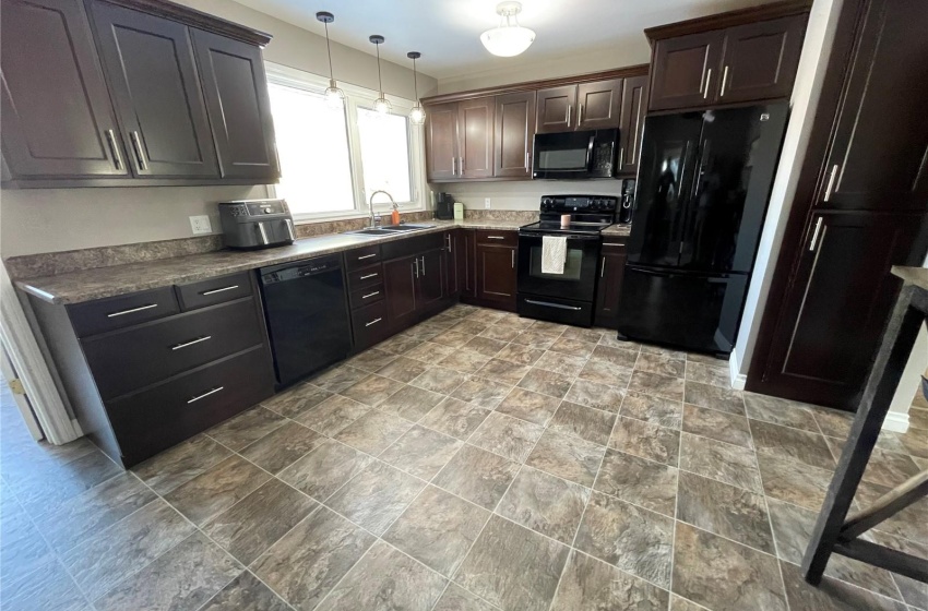 Kitchen with black appliances, light tile floors, dark brown cabinets, and decorative light fixtures