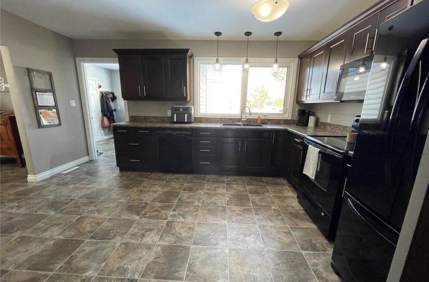 Kitchen with pendant lighting, sink, dark tile flooring, and black appliances