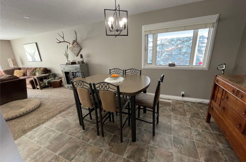 Dining area featuring an inviting chandelier, a textured ceiling, and dark tile flooring