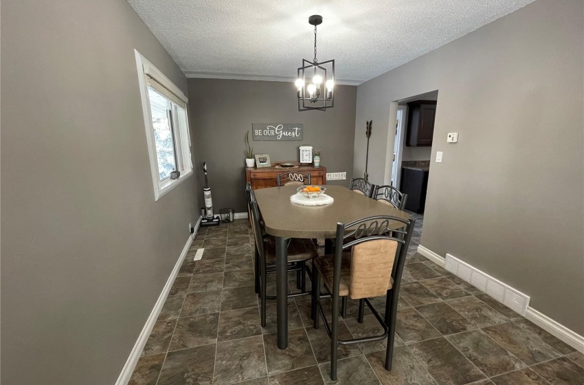 Dining space featuring an inviting chandelier, a textured ceiling, and dark tile flooring