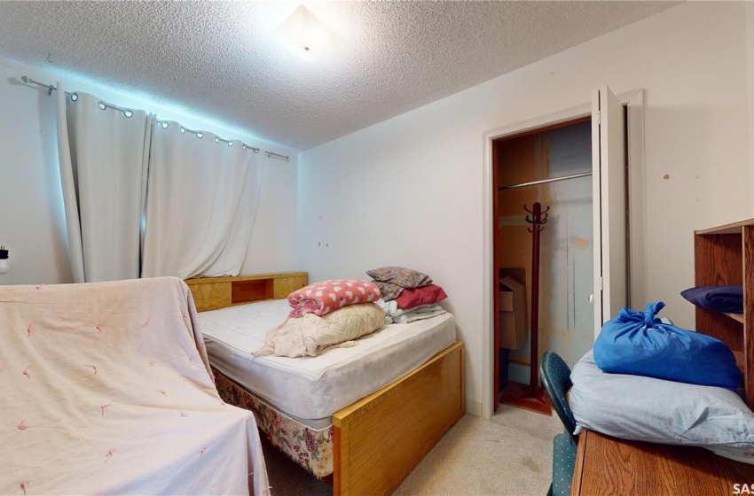 Bedroom with light colored carpet, a textured ceiling, and a closet