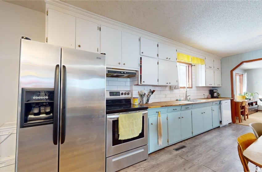 Kitchen with white cabinets, tasteful backsplash, light hardwood / wood-style floors, appliances with stainless steel finishes, and ceiling fan